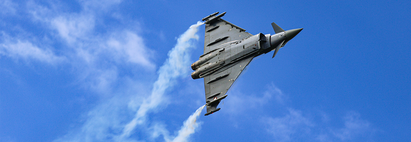 Eurofighter Typhoon fighter jet performing a manoeuvre against a bright blue sky